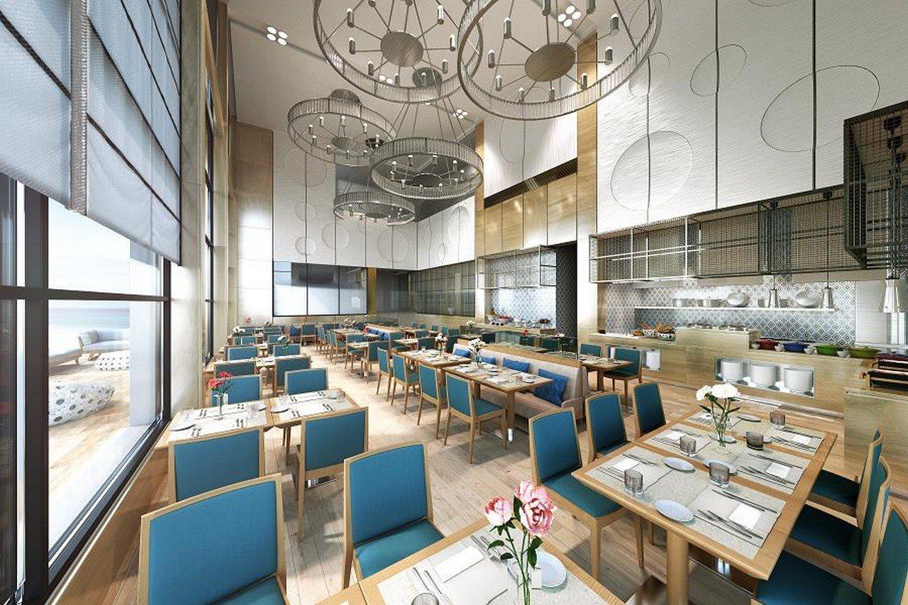 Grand Swiss-Belhotel Waterfront Seef Sanabis Exterior photo The photo shows the interior of a modern restaurant. The space features wooden flooring and is well-lit with large windows allowing natural light to enter. The dining area is filled with neatly arranged tables, each with light blue chairs and set wit