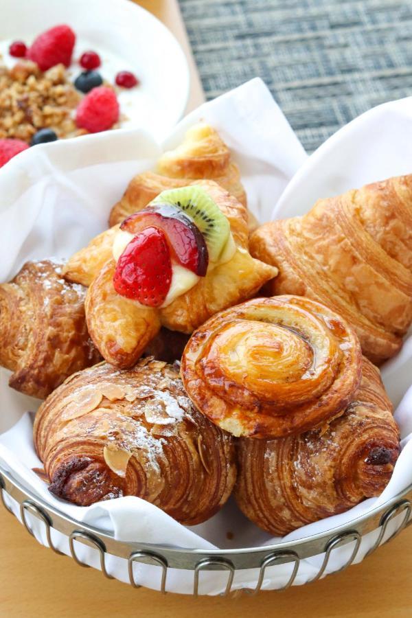 Grand Swiss-Belhotel Waterfront Seef Sanabis Exterior photo The photo showcases a variety of delicious pastries arranged on a white plate. There are croissants, possibly a fruit-filled pastry topped with sliced strawberries and kiwi, and a buttery, spiral-shaped pastry. Each item has a golden-brown color, ind